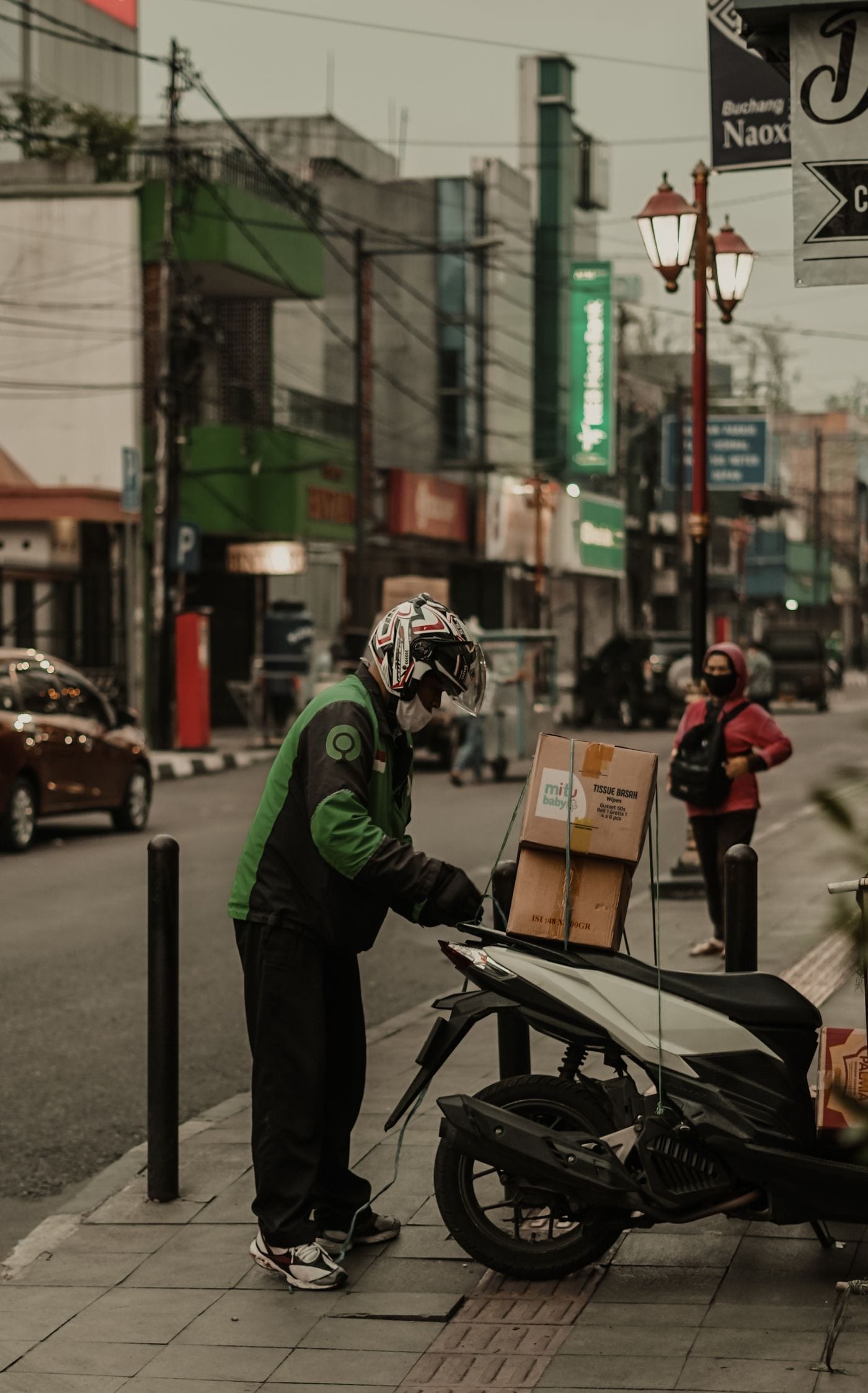 Entregador de moto com baú preto em rua urbana