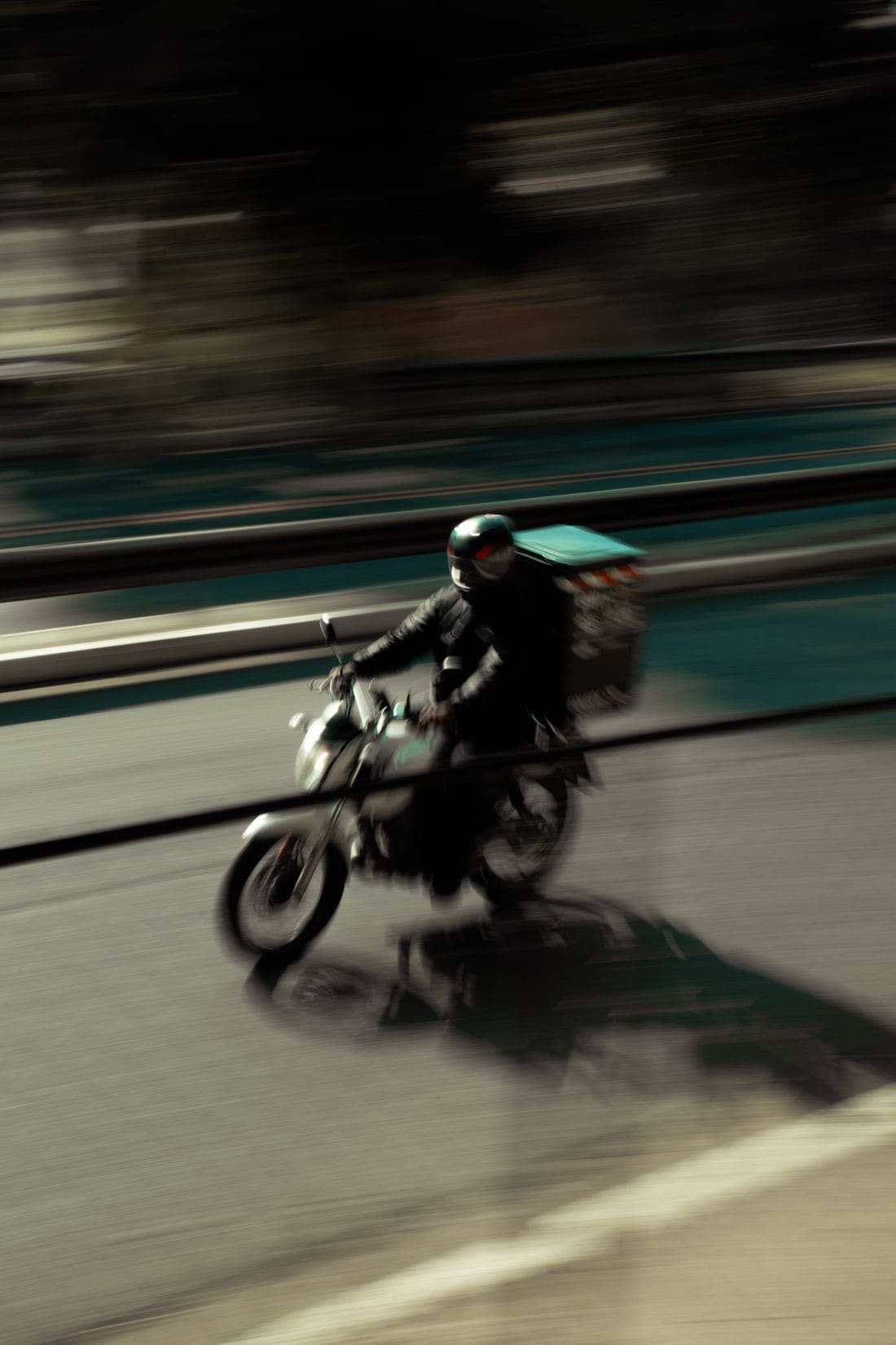 Entregador com bolsa térmica pilotando moto na cidade